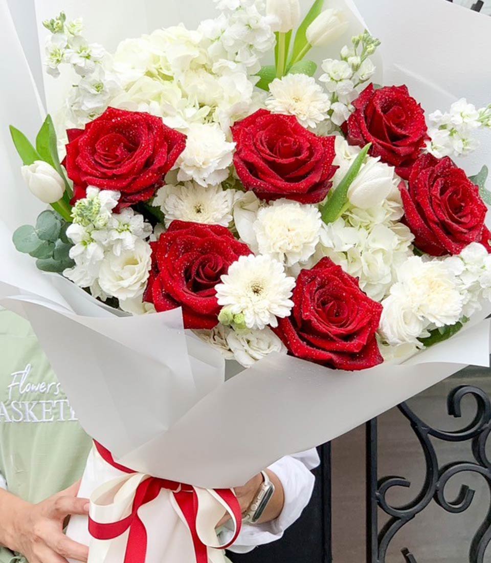 Fresh red roses and white filler flowers elegantly wrapped in romantic gift bouquet