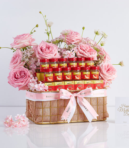Mother's Day gift basket with fresh pink roses, bird's nest bottles, and gold-trimmed wicker, finished with pink ribbon bow