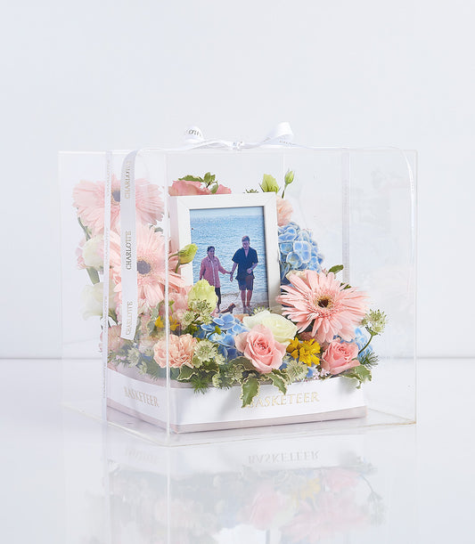 Clear acrylic Mother's Day gift box with fresh pink roses, blue hydrangeas, gerbera daisies and custom framed photo memory