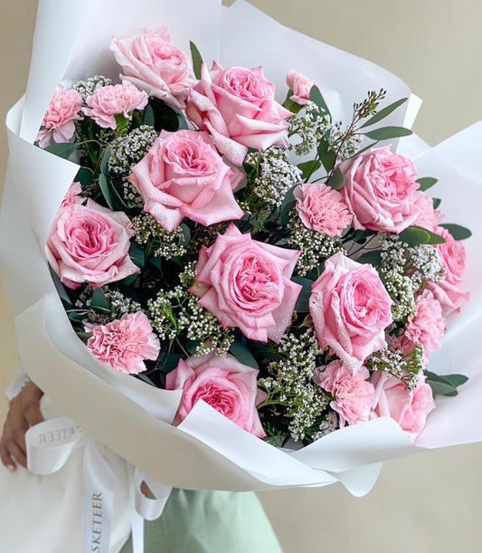 Fresh pink roses and carnations bouquet with white baby's breath, elegantly wrapped for gifting