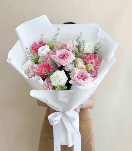 Large pink and white fresh flower bouquet with roses, gerbera daisies, and carnations wrapped in white paper