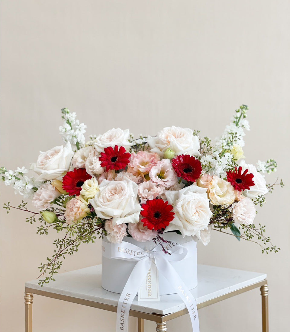 Premium white and red rose arrangement in elegant hatbox with gerbera daisies and stock flowers