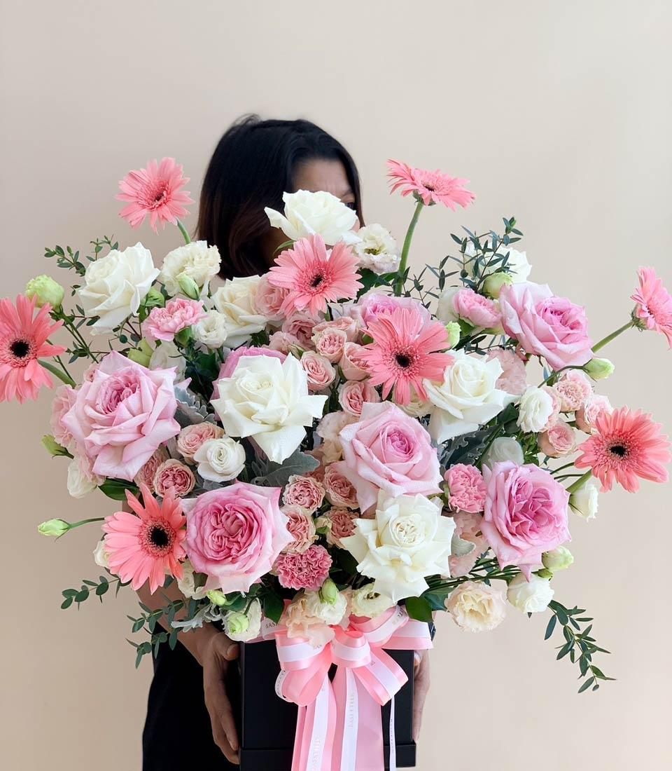 Pink and white rose bouquet in black box with striped ribbon, perfect for graduation congratulations