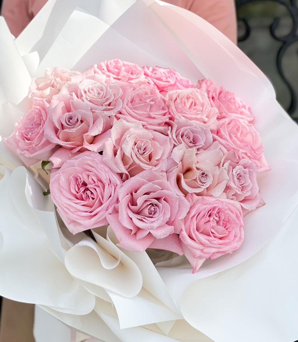 Fresh blushing pink rose bouquet with dewy petals in white paper wrapping