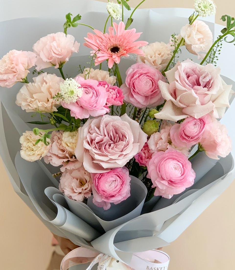 Premium pink and cream fresh flower bouquet with roses, ranunculus, and gerbera in elegant grey wrap