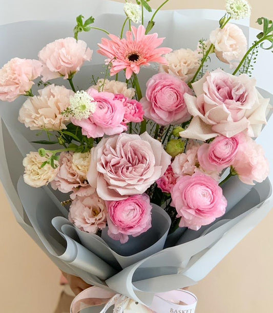 Premium pink and cream fresh flower bouquet with roses, ranunculus, and gerbera in elegant grey wrap