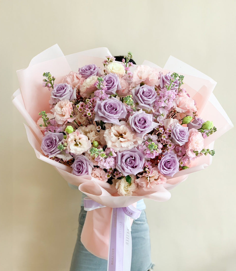 Lilac and blush fresh rose bouquet with ruffled pink carnations, wrapped in layered soft paper