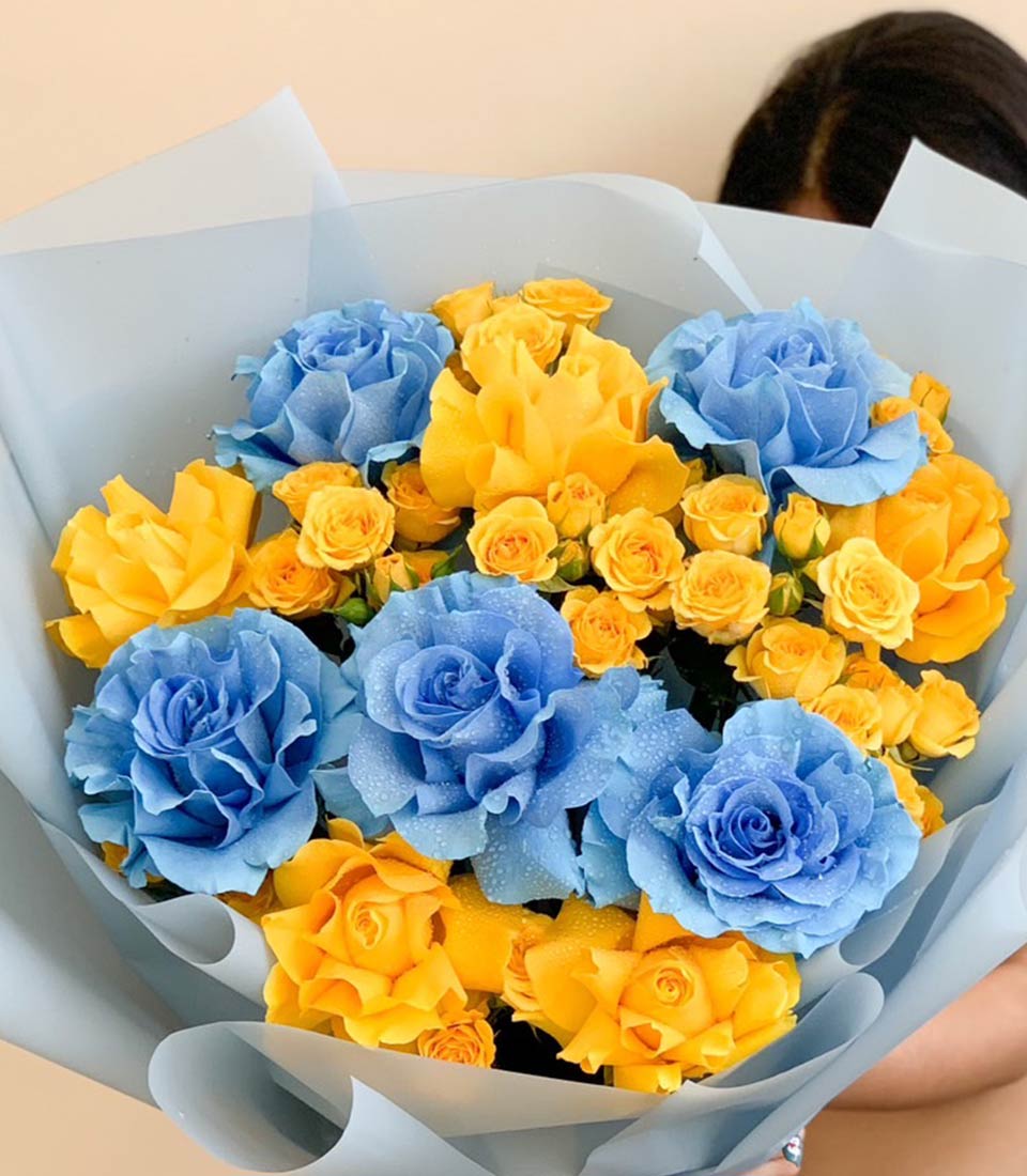 Vibrant blue and yellow rose bouquet with fresh water-kissed petals, graduation gift wrapped in soft tissue