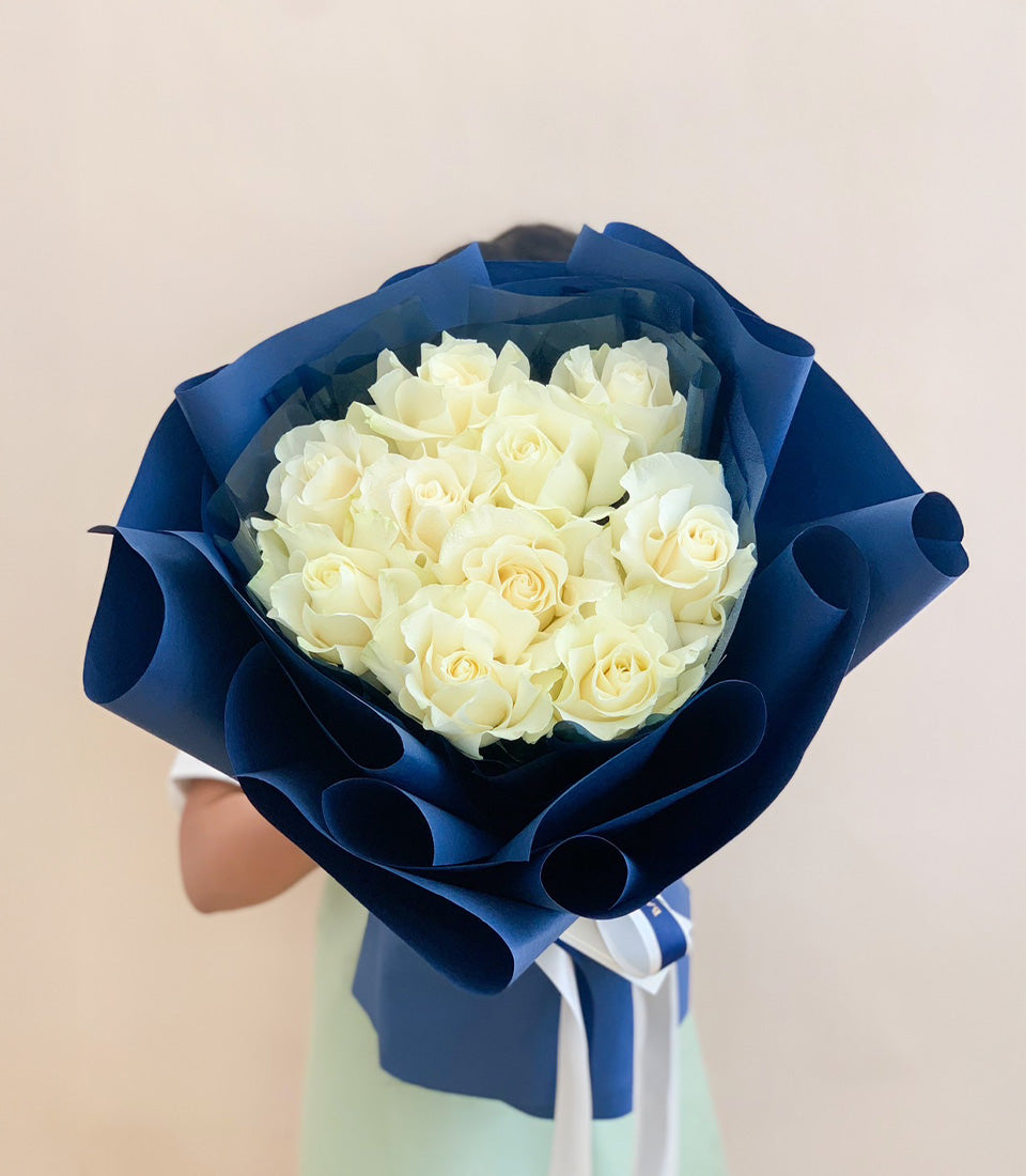 Luxury white rose bouquet with dark blue wrapping and striped ribbon
