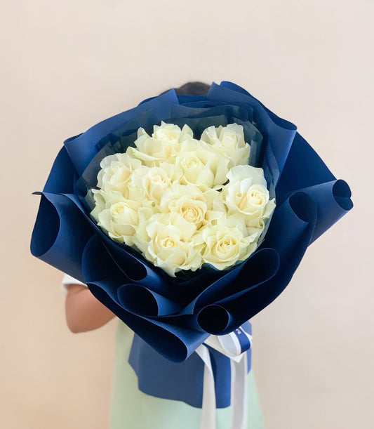 Luxury white rose bouquet with dark blue wrapping and striped ribbon