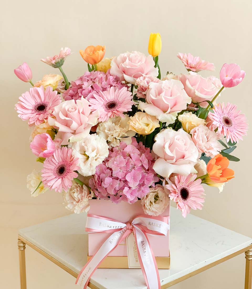Luxury pink and pastel floral arrangement in gift box with roses, gerberas, hydrangeas, and tulips for graduation