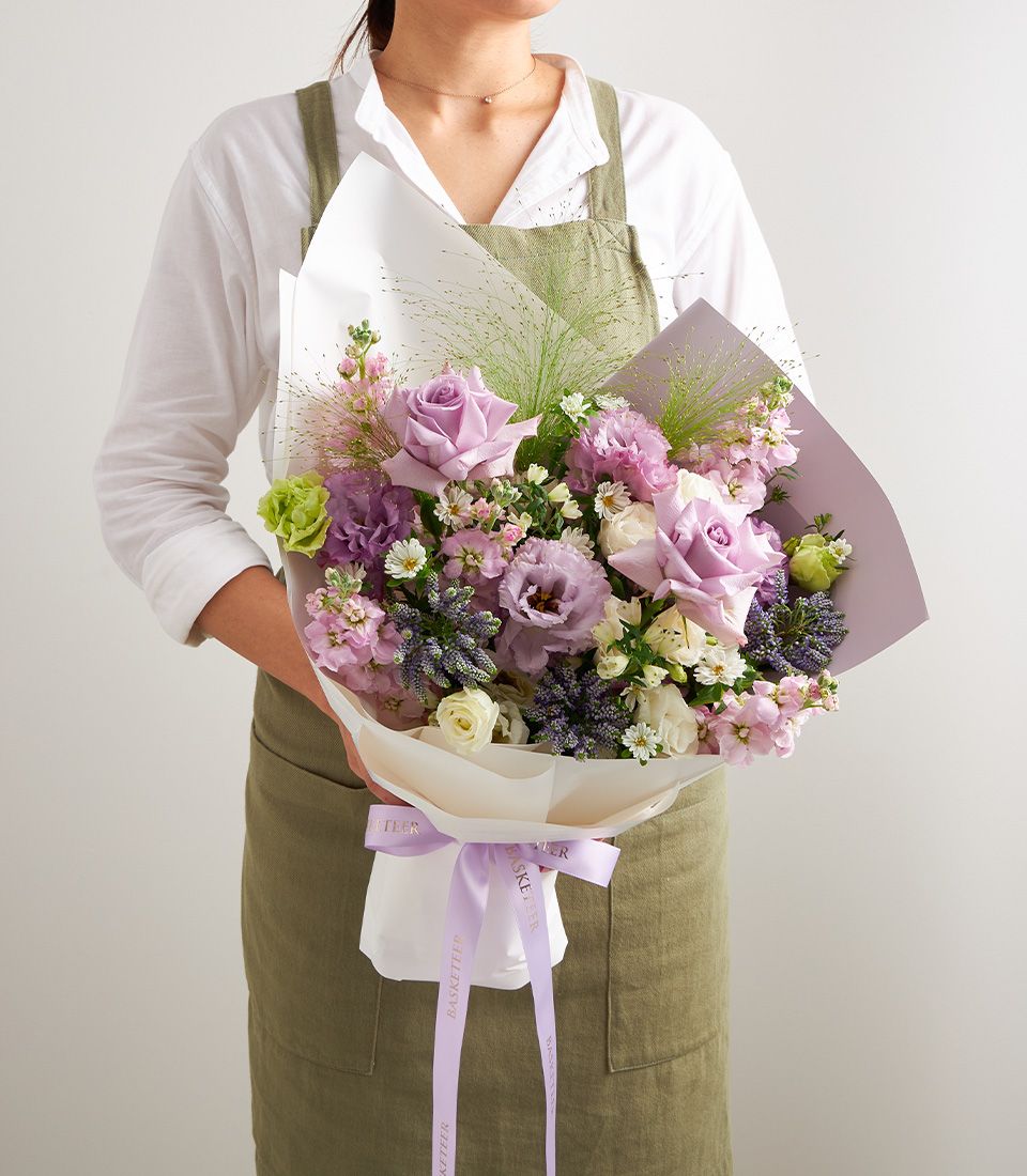 Purple pastel mixed bouquet with lavender roses and lisianthus in white paper wrap