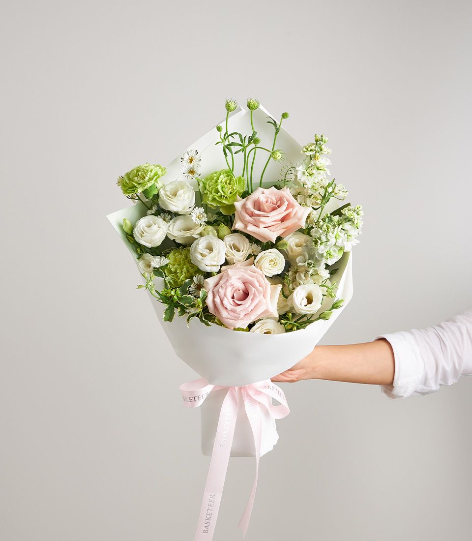 Fresh pink roses, white eustoma, and green carnations petite bouquet with white paper wrap and pink ribbon