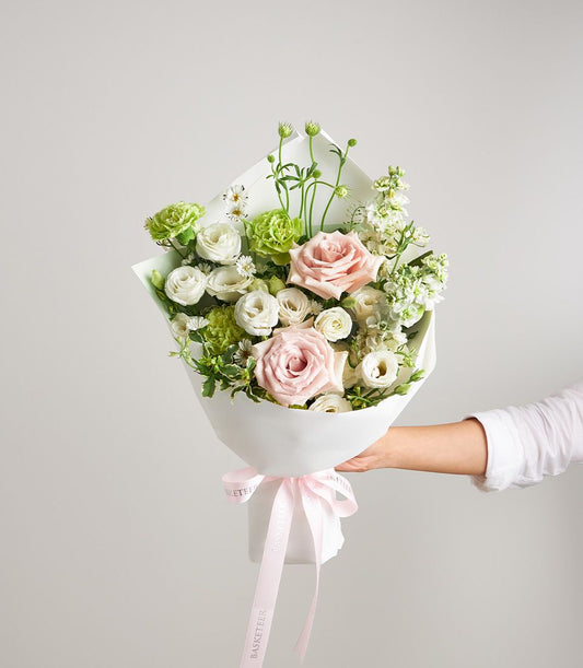 Fresh pink roses, white eustoma, and green carnations petite bouquet with white paper wrap and pink ribbon