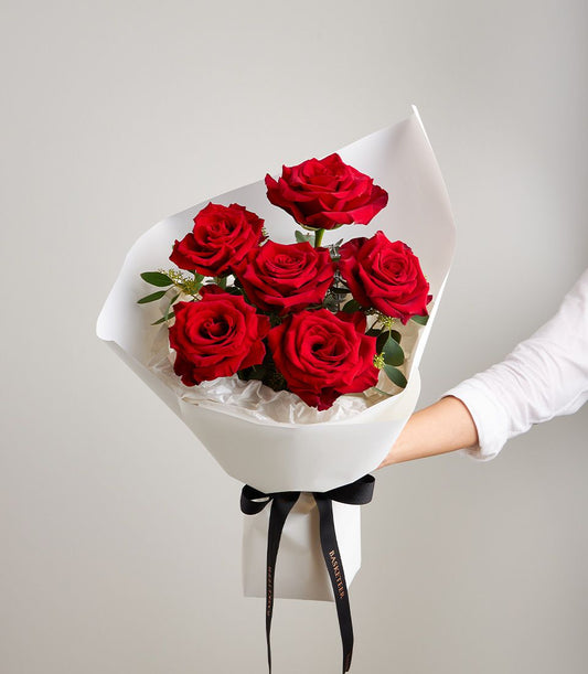 Vibrant red rose bouquet with white wrap and black Basketeer ribbon, perfect for anniversaries