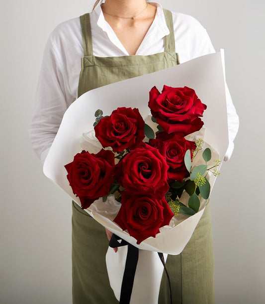 Deep red roses with eucalyptus in white paper and black ribbon, anniversary gift bouquet