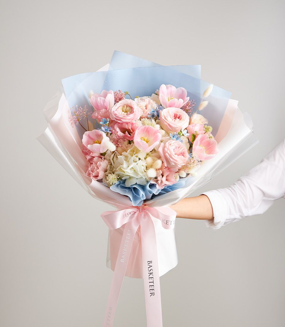 Pastel pink and blue fresh flower bouquet with roses, tulips and hydrangeas, tied with Basketeer ribbon