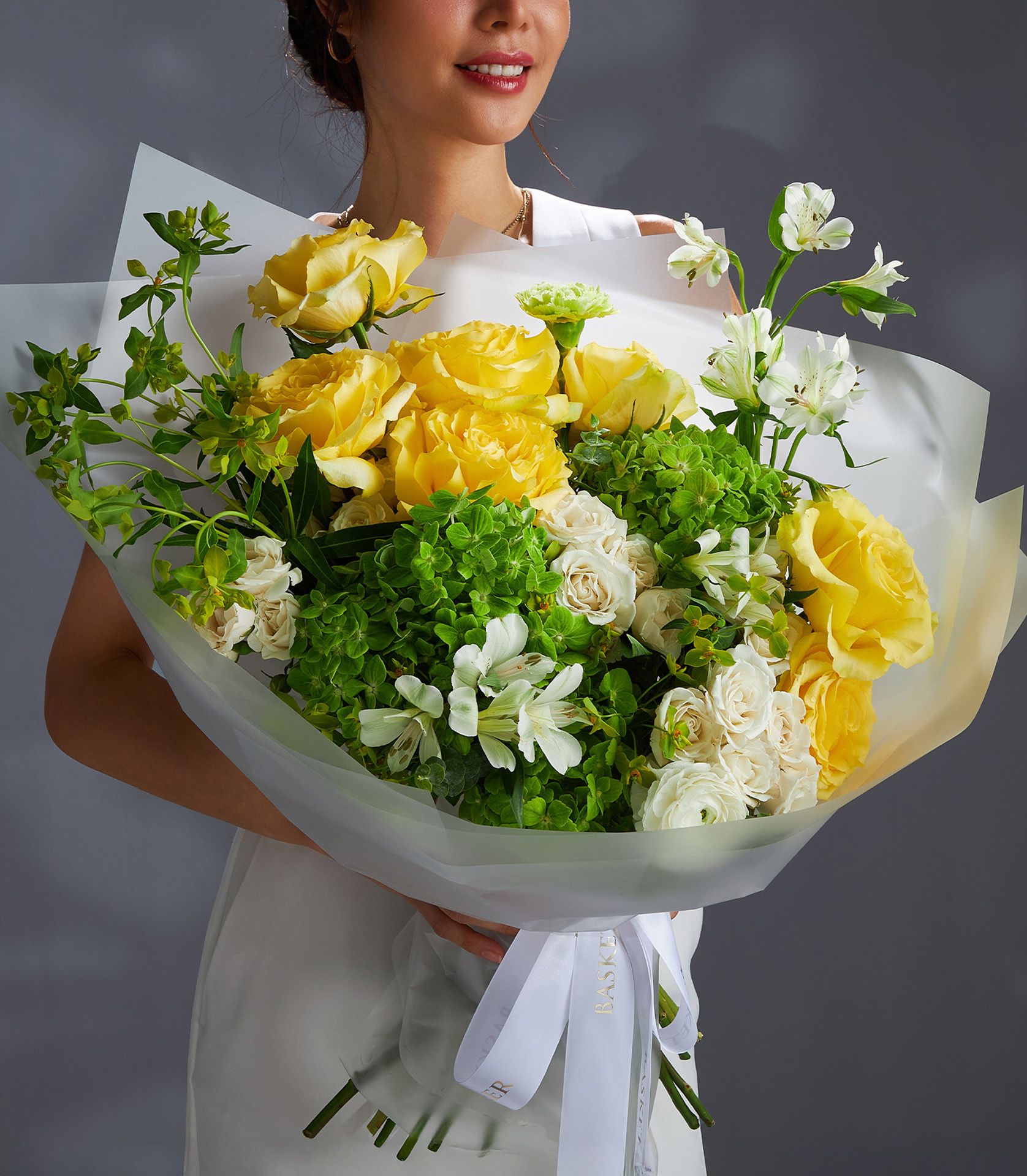 Vibrant yellow roses and green hydrangea bouquet with white roses and greenery, wrapped in white paper