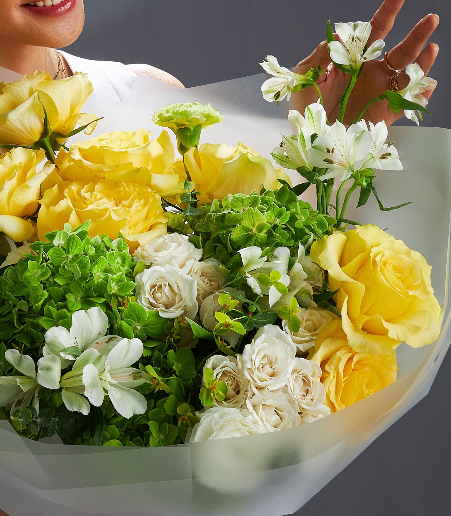 Vibrant yellow roses and green hydrangea bouquet wrapped in white paper