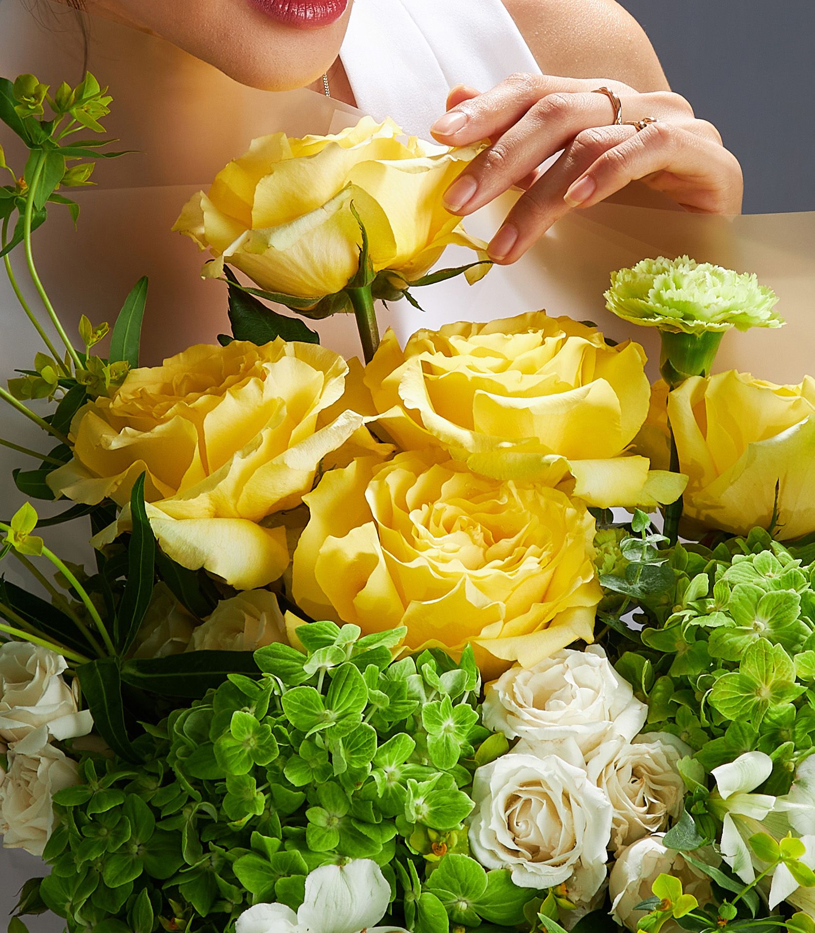 Bright yellow roses with green hydrangea and white flowers in beige wrapping, fresh bouquet for gifting