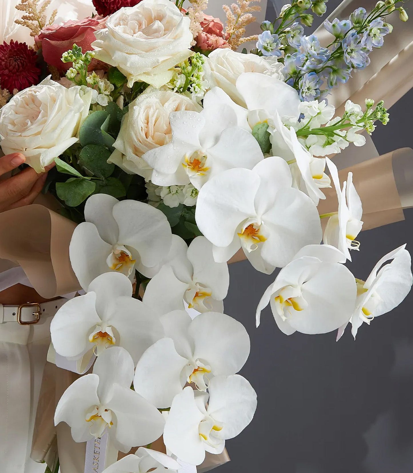 Luxury white roses and phalaenopsis orchids with delicate filler flowers, wrapped in kraft paper with white ribbon