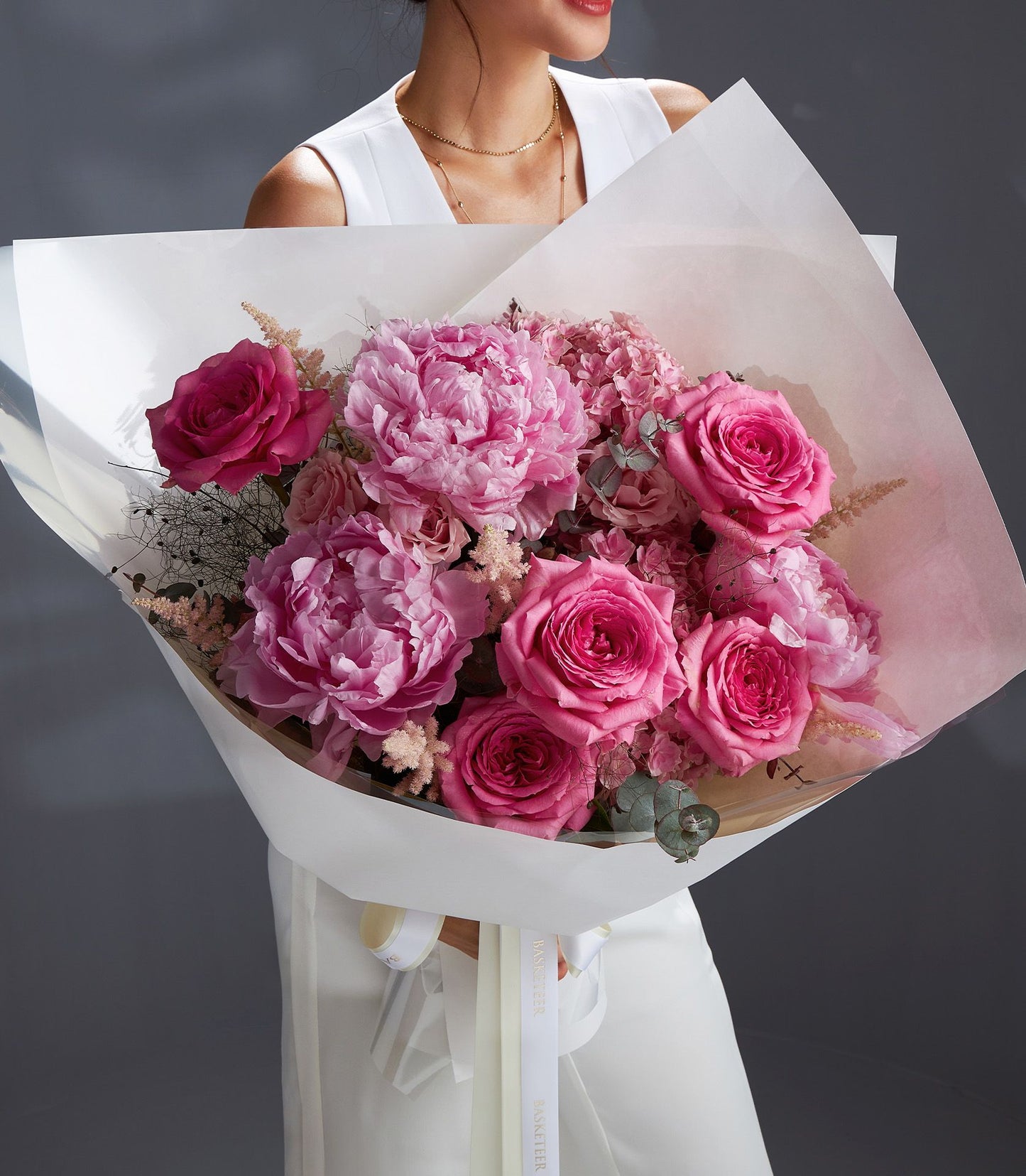 Luxury pink peony and rose bouquet with eucalyptus, wrapped in white paper and cream ribbon