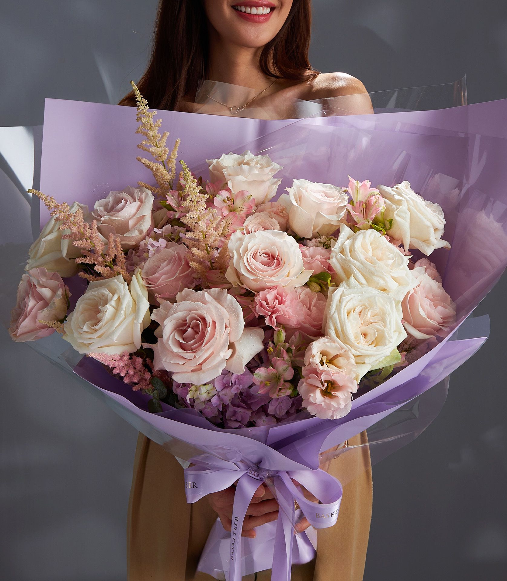Large pink and white Ecuadorian rose bouquet with hydrangeas and astilbe, wrapped in purple cellophane