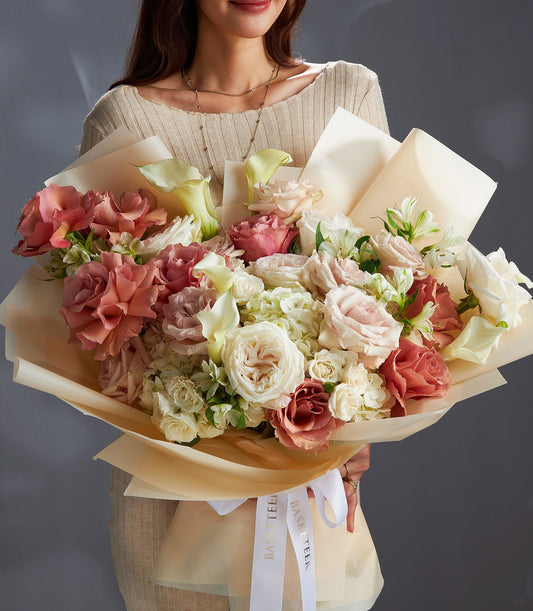 Ethereal white and blush rose bouquet with calla lilies, fresh-cut and wrapped in cream paper