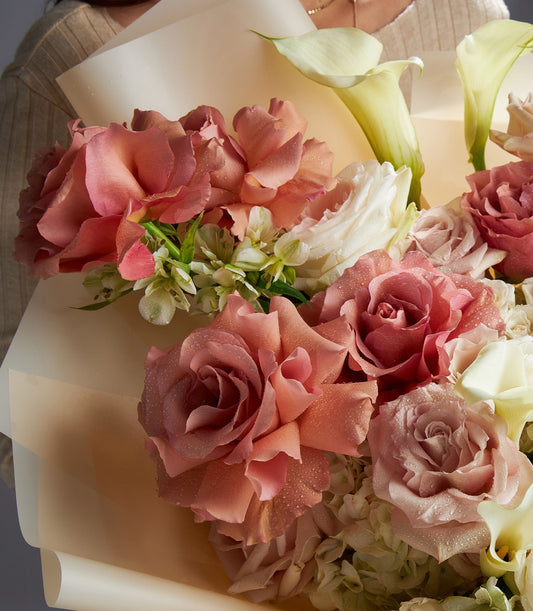 Ethereal white and blush rose bouquet with calla lilies and hydrangeas, wrapped in beige paper