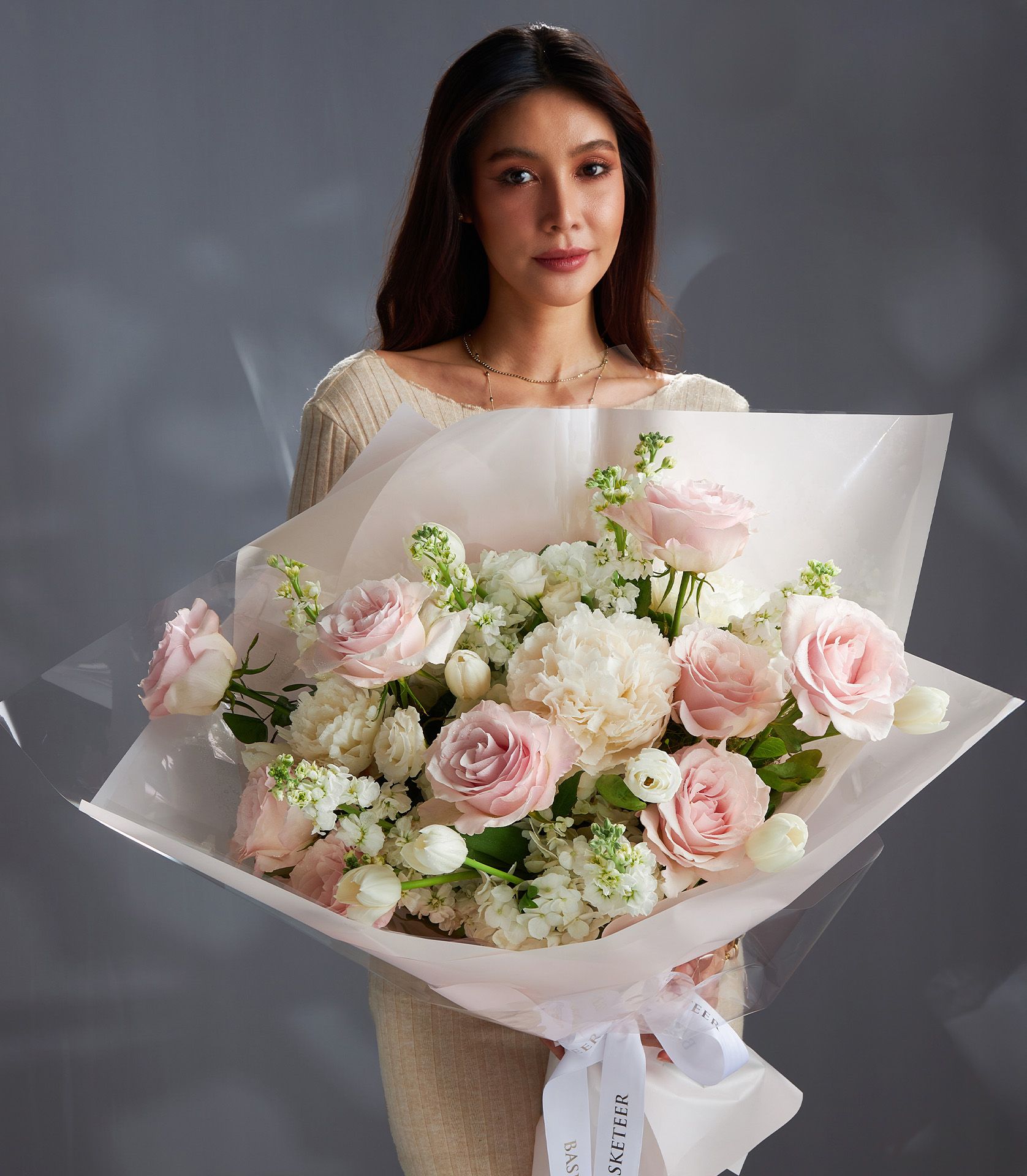 Light pink roses and white peonies bouquet with tulips and filler flowers, wrapped in pink paper and ribbon