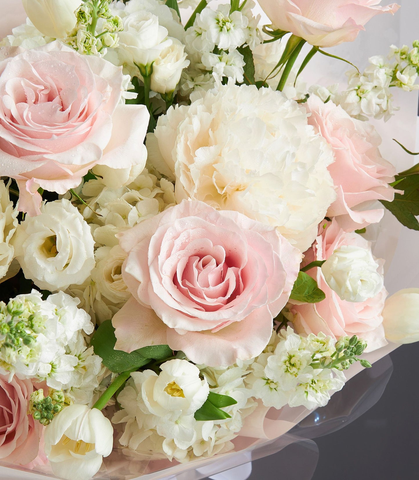 Light pink roses and white peonies bouquet with hydrangea and greenery, wrapped in peach paper