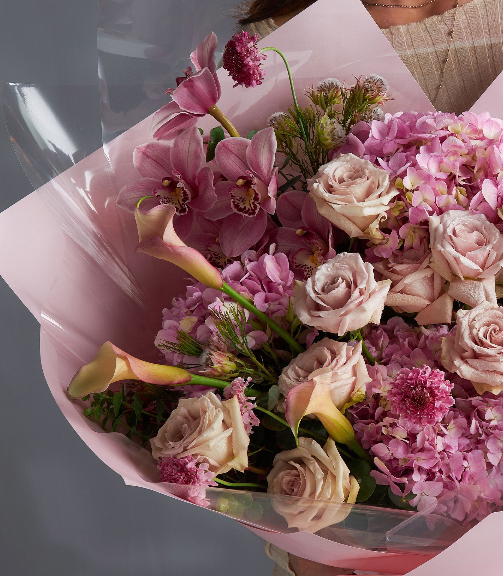 Quicksand rose and orchid bouquet with peach calla lilies and hydrangea, wrapped in pink cellophane
