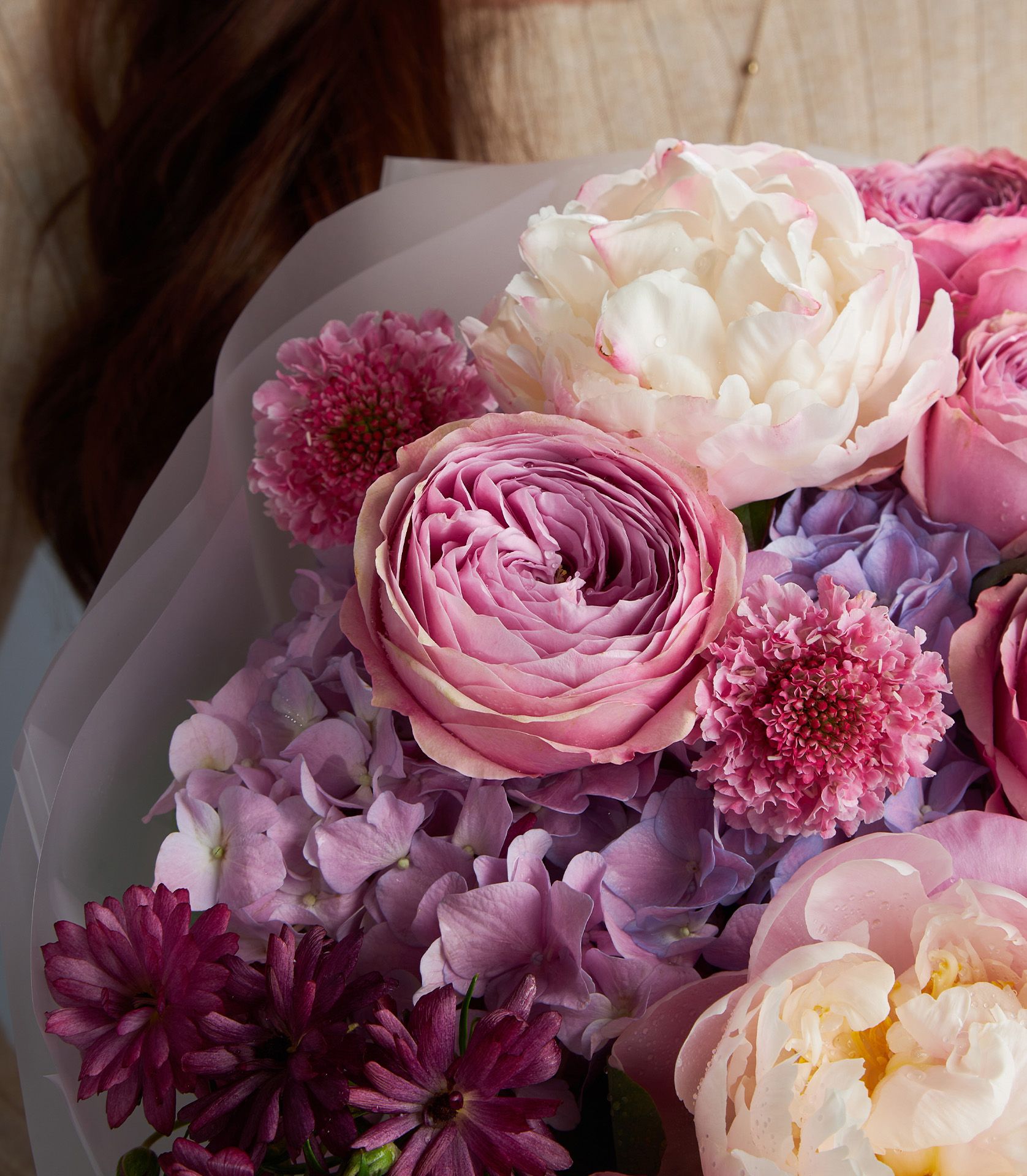 Luxury romantic rose bouquet with peonies, garden roses, hydrangeas and burgundy chrysanthemums in soft purple wrapping