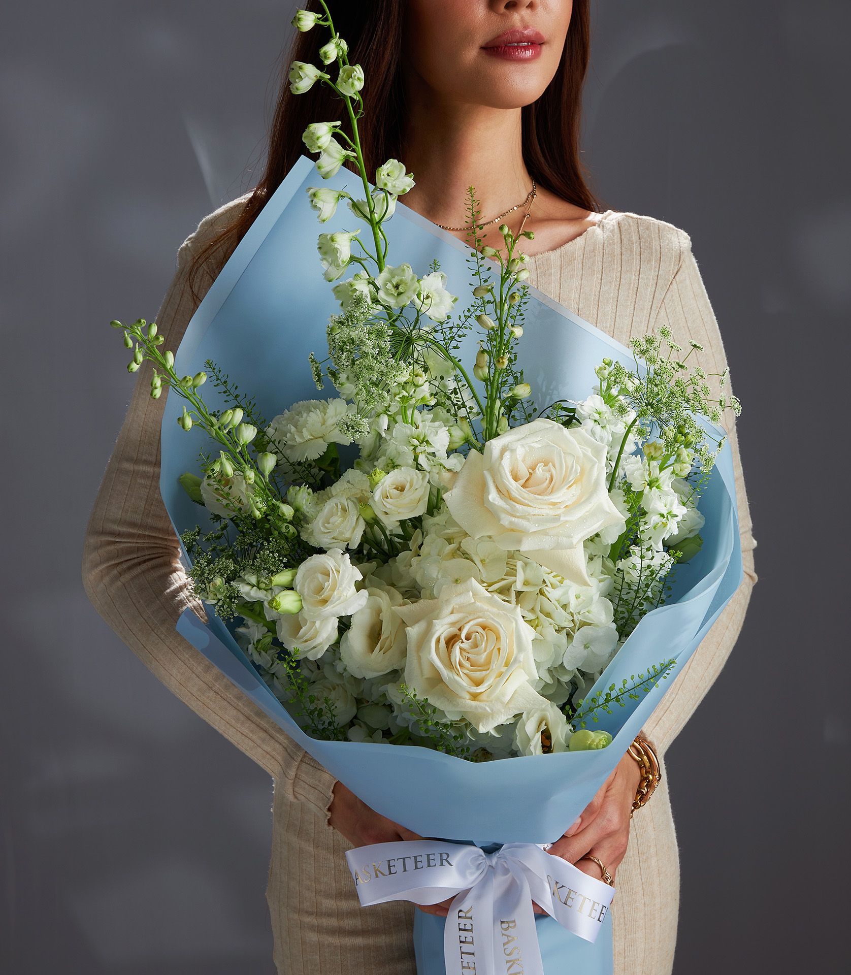 Elegant white rose and hydrangea bouquet wrapped in soft blue paper with white ribbon