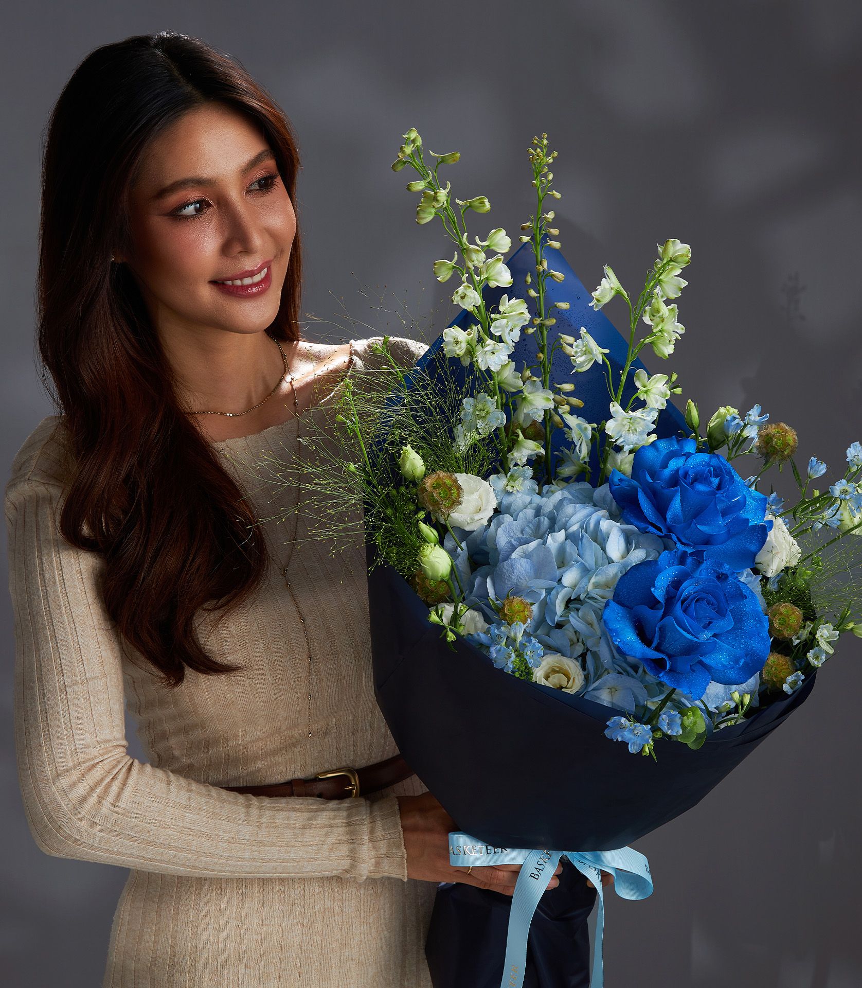 Premium blue roses and hydrangea bouquet wrapped in dark paper with light blue ribbon
