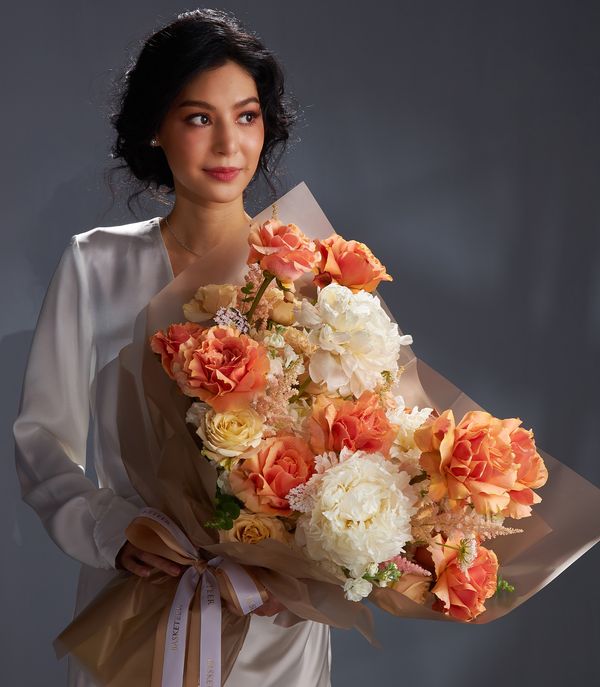 Luxury peony and rose bouquet in peach, coral, and white with Ecuador roses, wrapped in brown paper with white ribbon