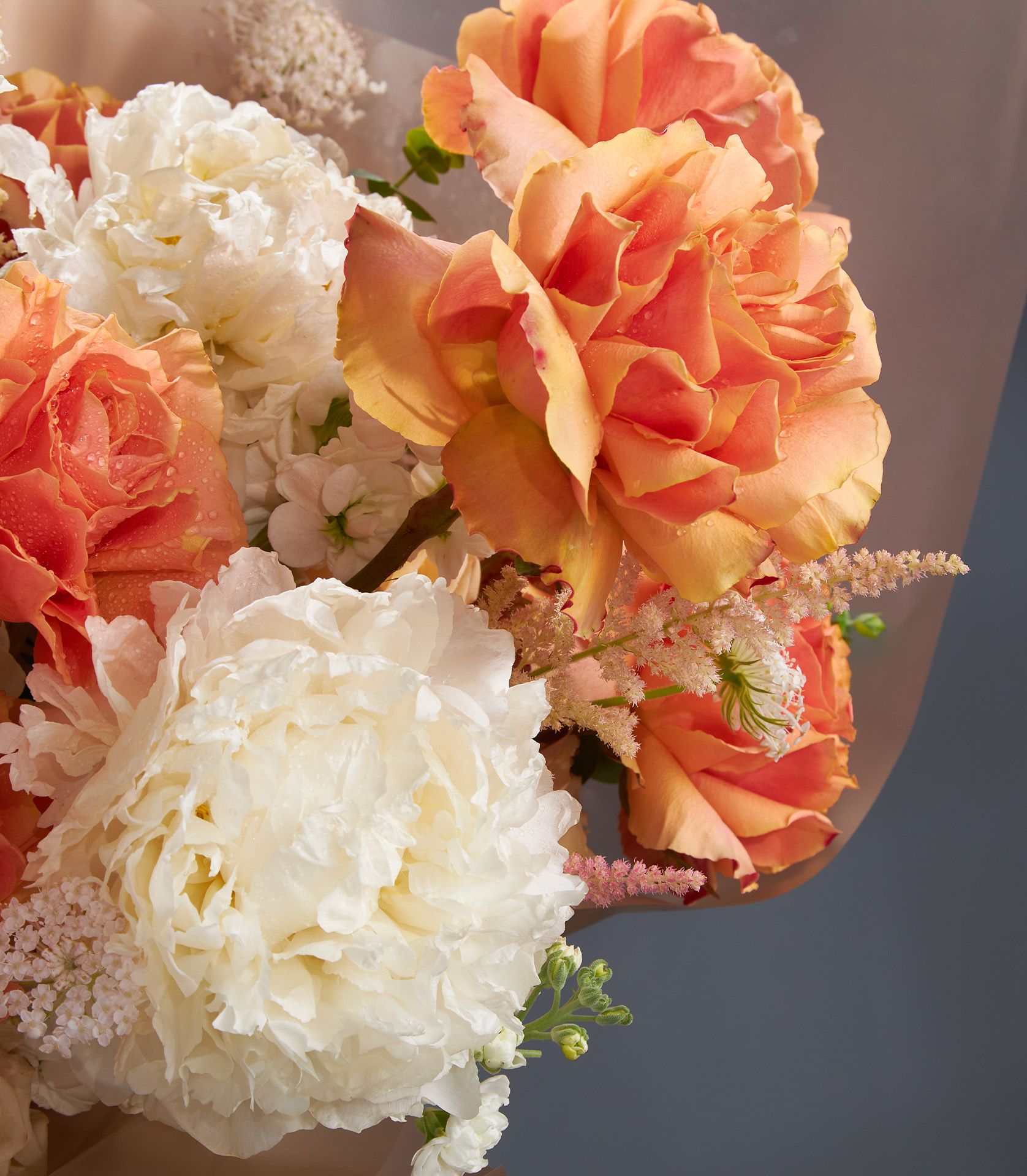 Luxury peony and rose bouquet with creamy white and coral blooms, wrapped in kraft paper