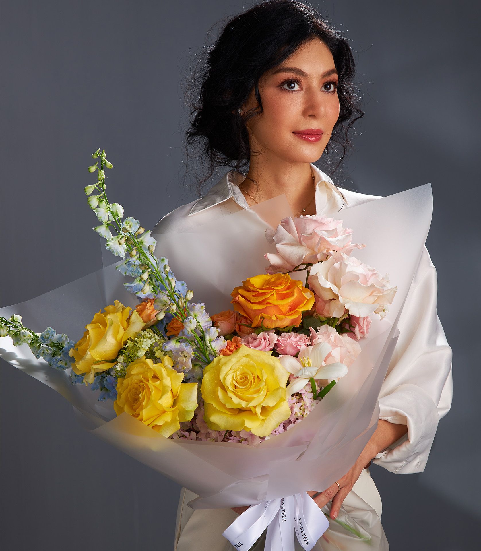 Radiant Bloom rose bouquet with yellow, orange, and pink roses tied with Basketeer ribbon