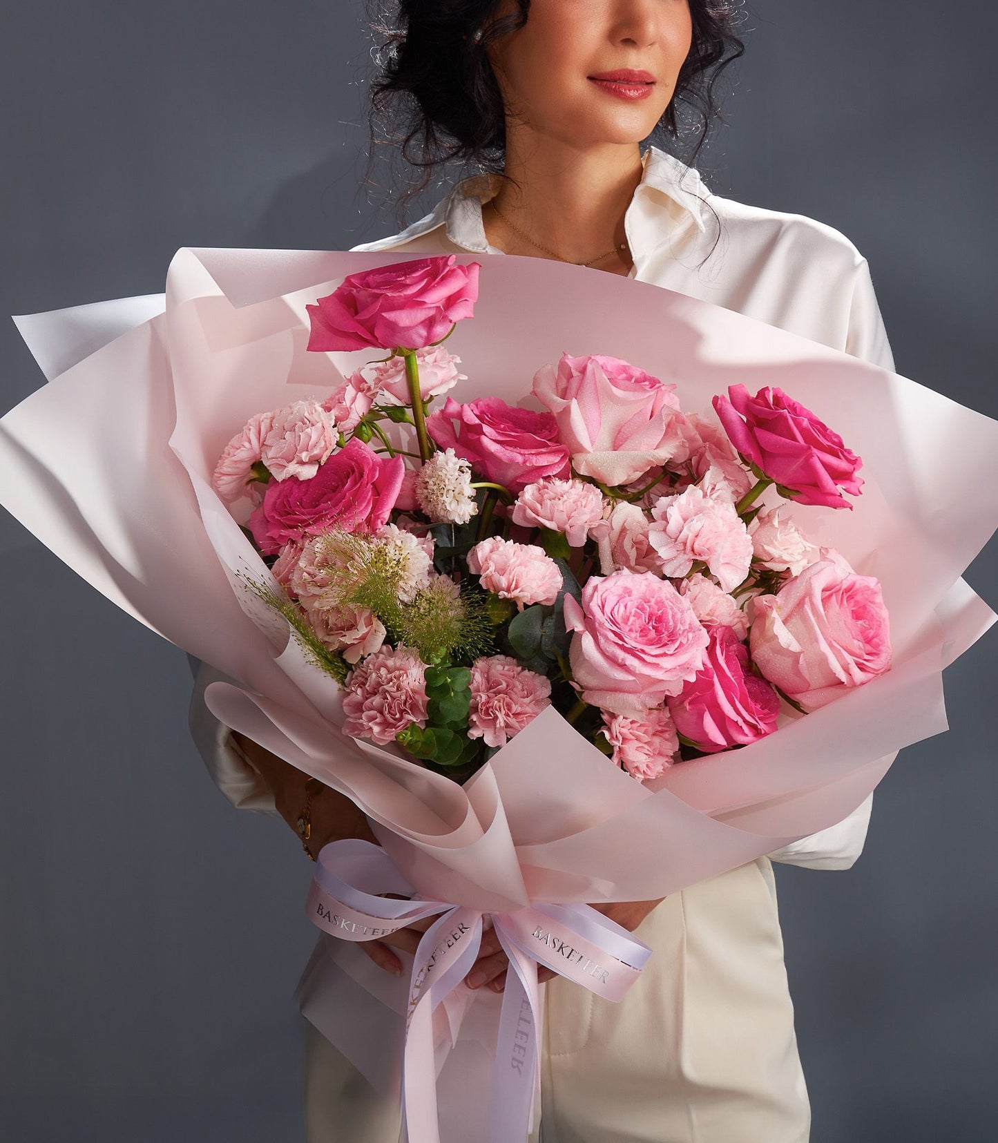 Blush pink rose and carnation bouquet with white accents, wrapped in soft pink paper and tied with ribbon