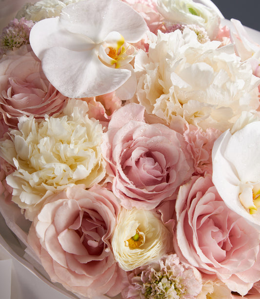 Luxury mixed peony bouquet with roses, orchids, and fresh filler flowers in soft pink and cream