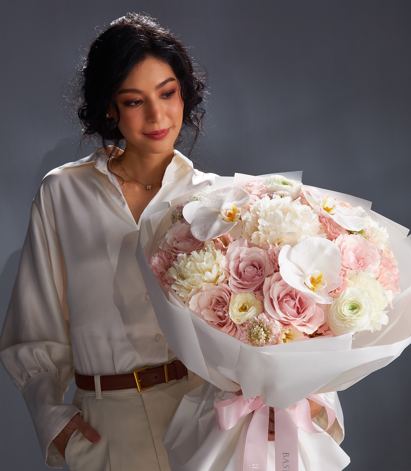 Luxury peony and rose bouquet in soft pink and white with ranunculus and orchids, wrapped in elegant white paper and tied
