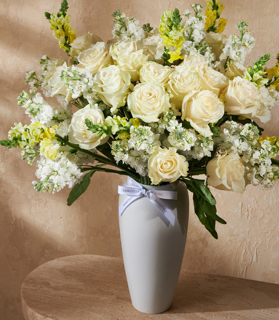 Ivory roses and white flowers in ceramic vase with yellow snapdragons, luxury gift arrangement