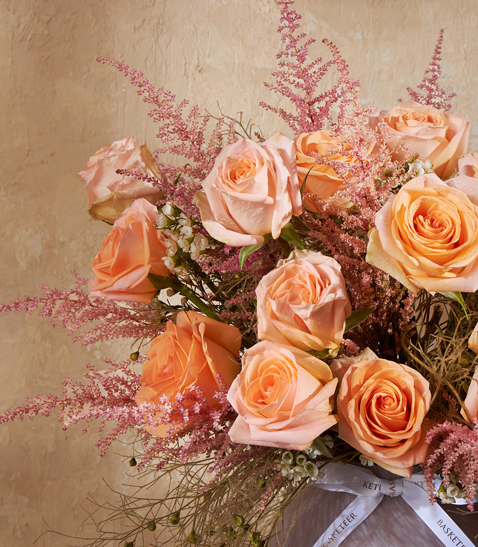 Peach and light orange roses with pink astilbe in fresh flower vase arrangement
