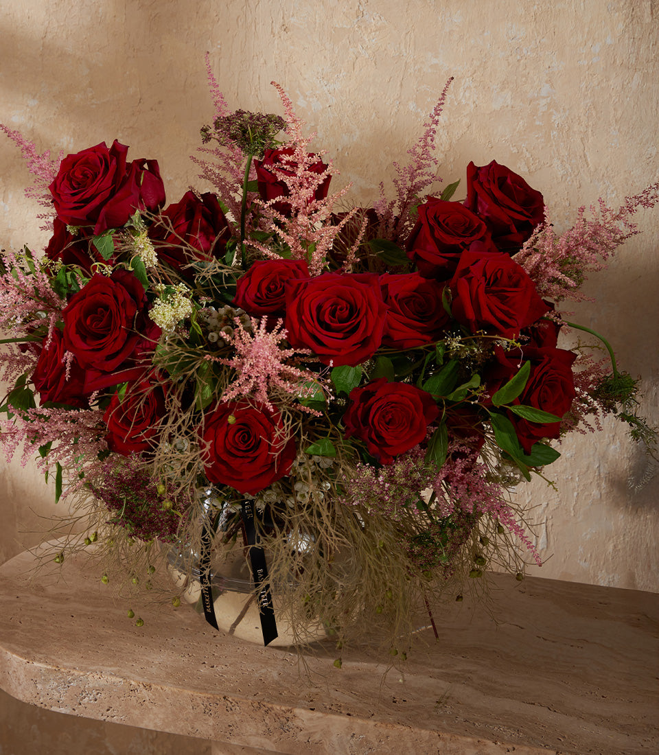 Deep red roses with pink astilbe in silvered glass vase, premium fresh flower arrangement