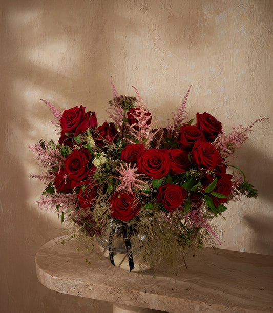 Deep red rose arrangement with pink astilbe in silver vase with black ribbon