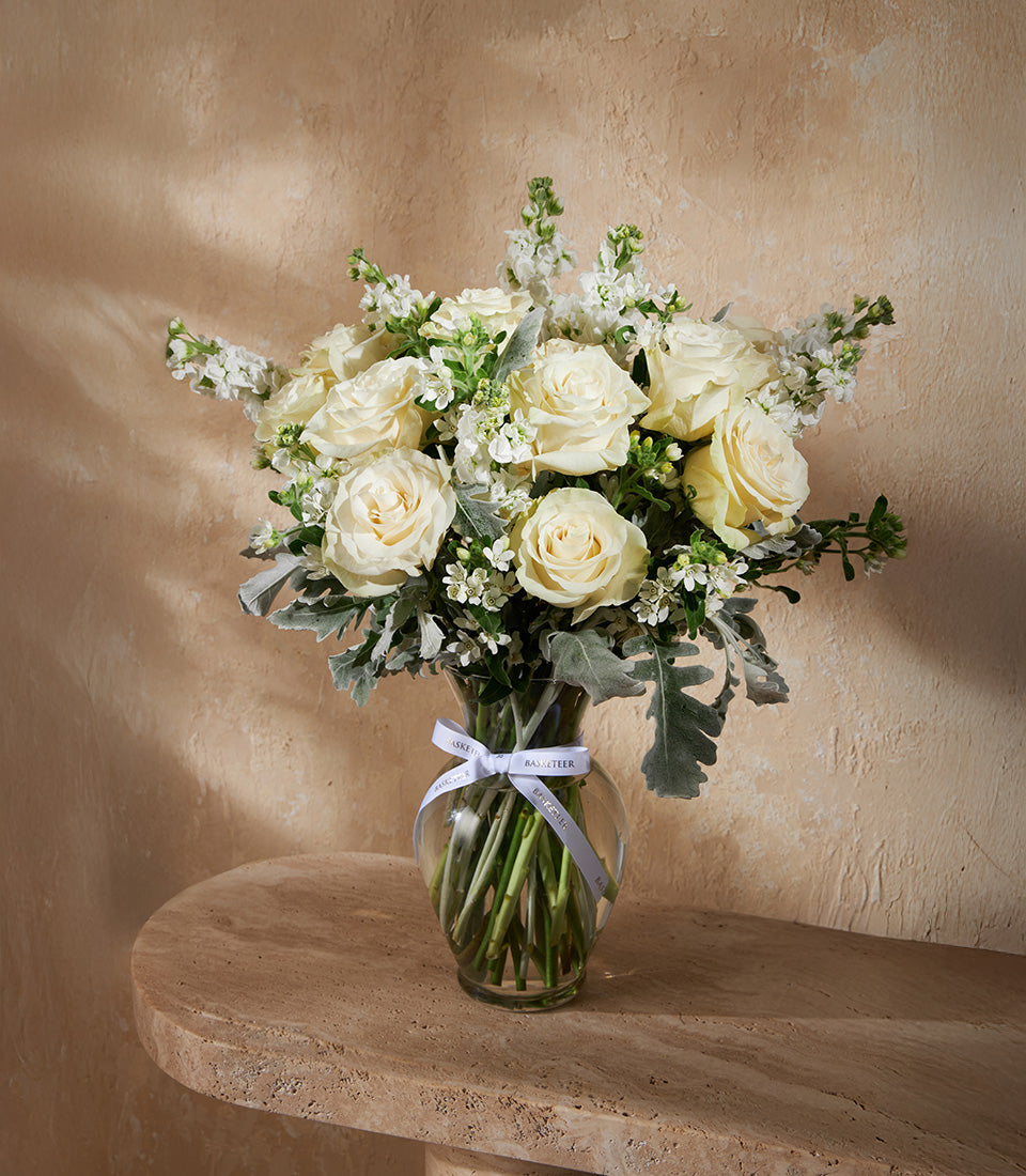 Ivory Elegance clear glass vase with white roses and dusty miller foliage, white ribbon detail