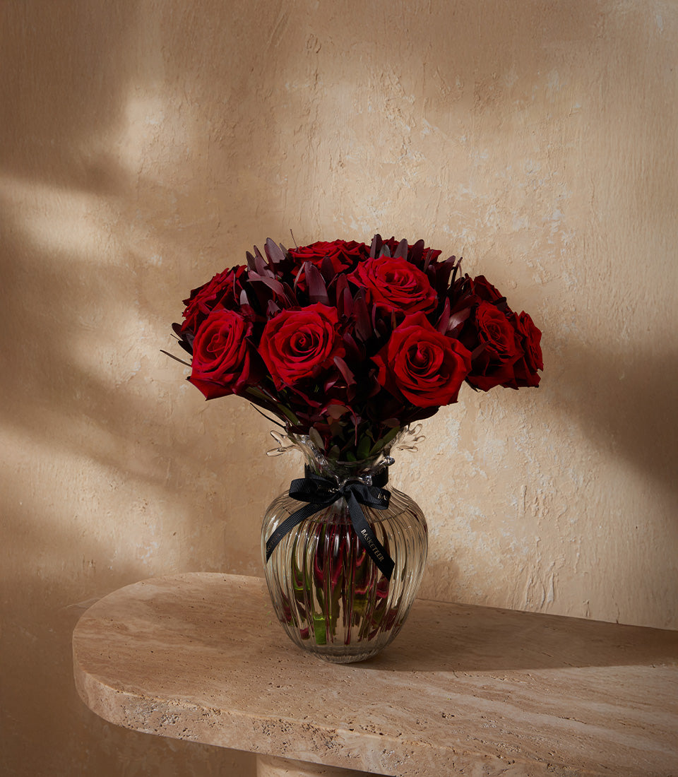 Deep red rose bouquet in ribbed glass vase with black ribbon, premium fresh flowers for gifting