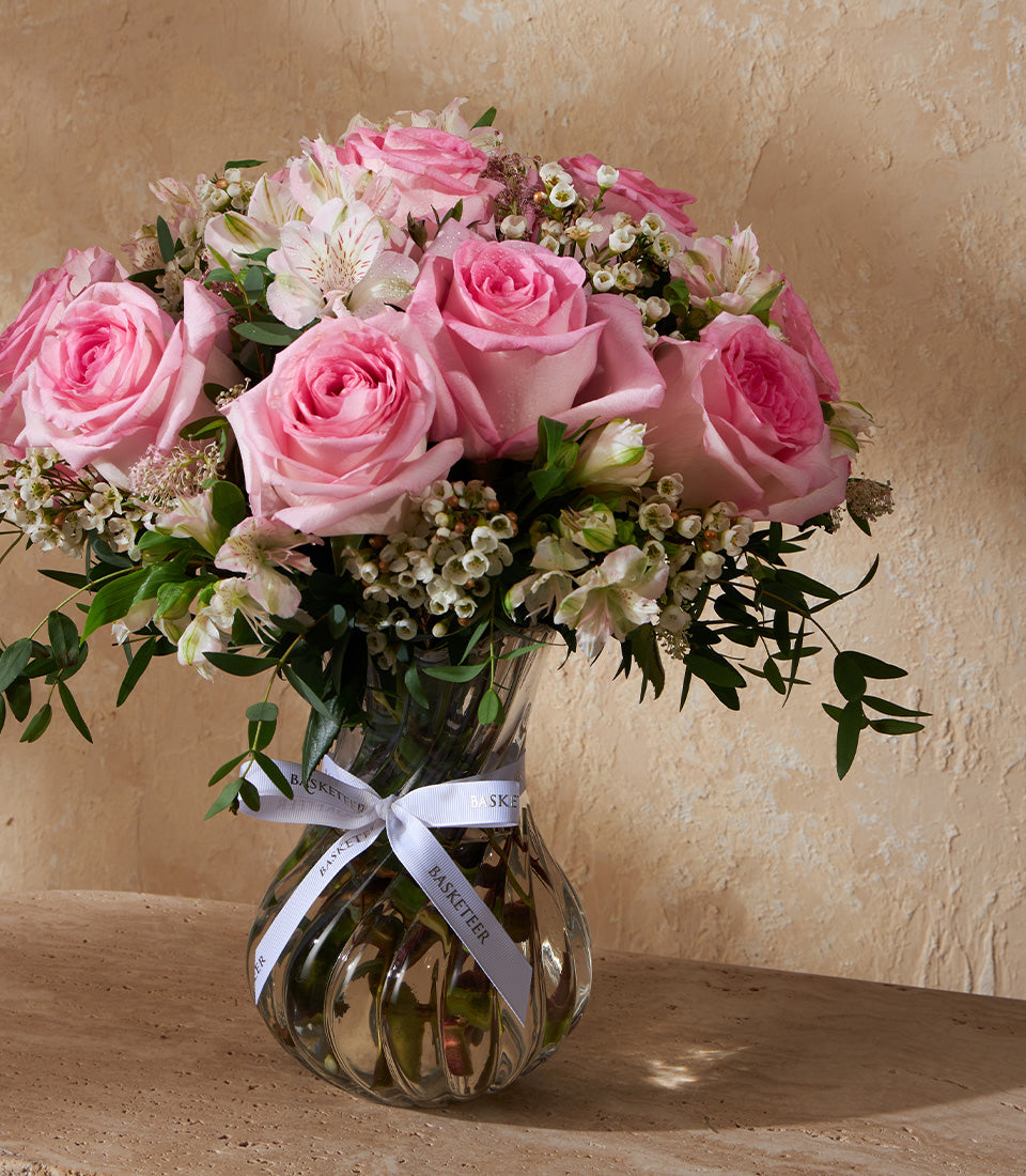 Deep red roses in clear ribbed glass vase with white ribbon, fresh flowers for elegant gifting