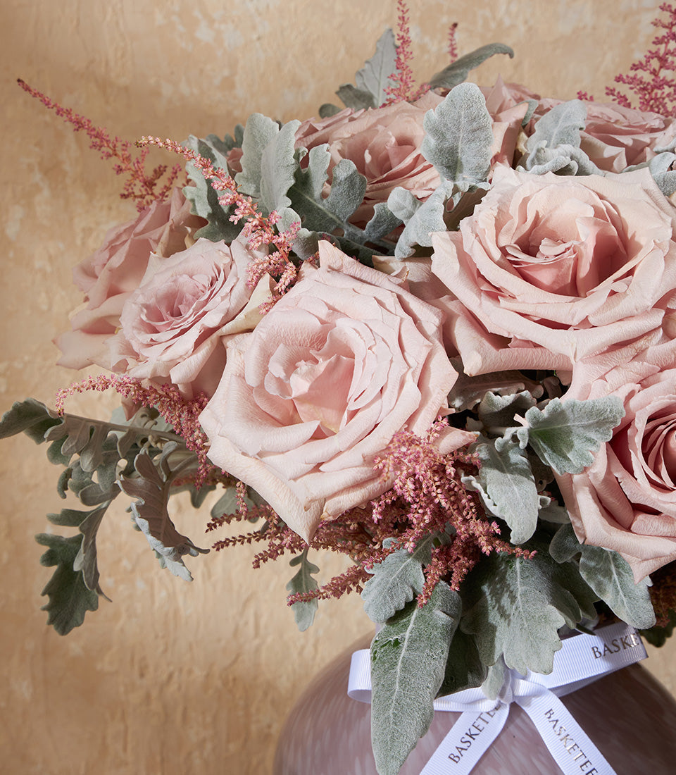 Light pink rose bouquet with dusty miller and astilbe filler in nude ceramic vase with white ribbon