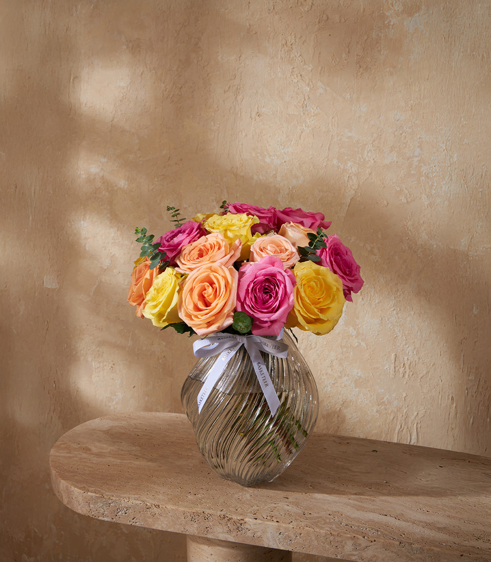 Radiance Trio rose vase with vibrant yellow, orange, and pink roses in clear glass